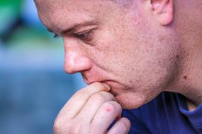 Profile portrait of the thinking male, holding mouth with the hand