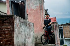 Boy with Bicycle at old shabby house