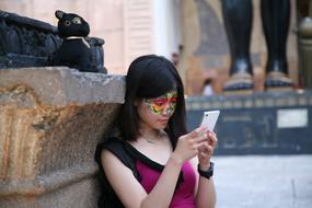 young girl with painted face looking at smartphone