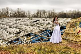 Girl in the dress, posing near the construction, among the colorful and beautiful plants