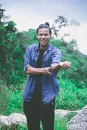 Smiling boy in Assam, India, among the green plants and rocks