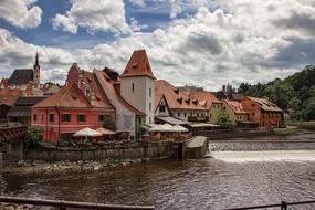 Beautiful and colorful buildings, among the green plants, in ÄeskÃ½ Krumlov, Czech Republic, under the blue sky with clouds