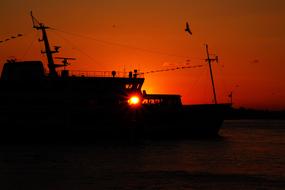 The silhouette of a fishing boat at sunset