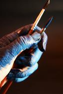 Close-up of the hand with shiny paint brushes