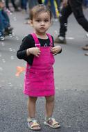 little girl in a pink sundress on a city street