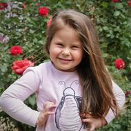 Portrait of the smiling girl, near the beautiful red flowers in summer