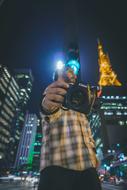 a man with a camera on the background of skyscrapers at night