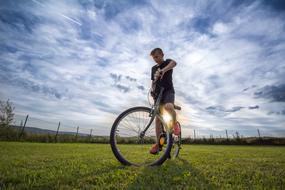 boy with bike on the field in the bright sun