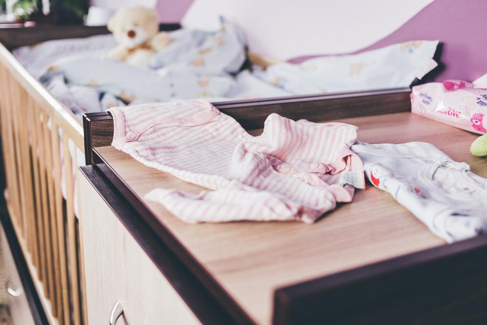 Cute and colorful baby clothes and Teddy bear on the furniture
