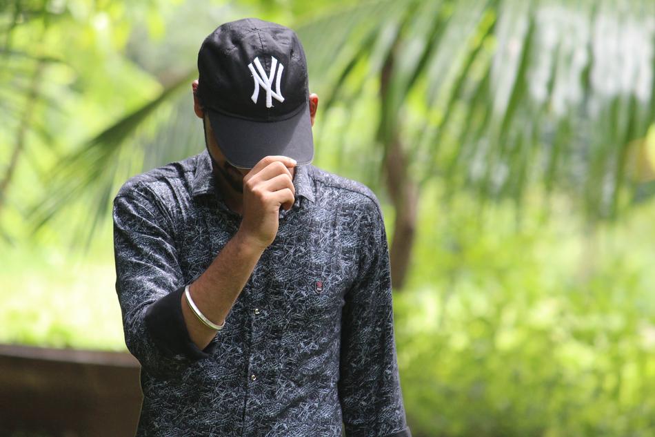 man covers his face with a black cap