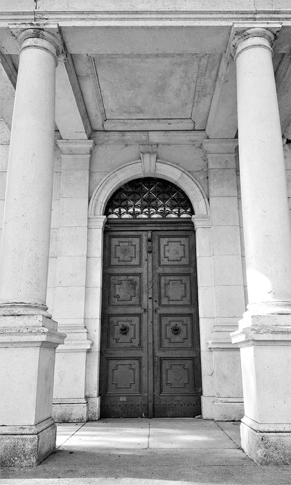 Black and white of the beautiful architecture with the columns and patterned door