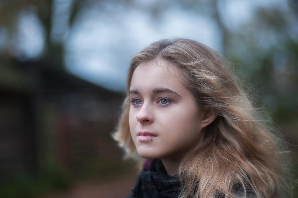 Portrait of the girl with blue eyes at blurred background, in autumn