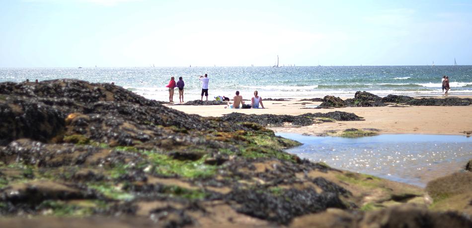 people on the beach by the rocks