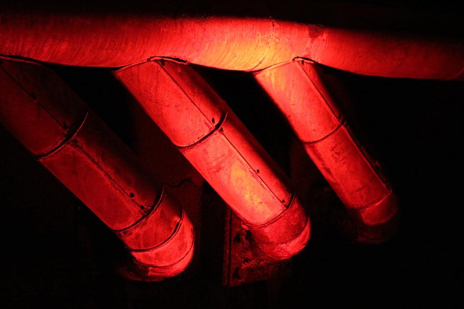 Metal pipes in red and orange colors, among the darkness