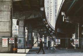 Person walking under the constructions, among the buildings