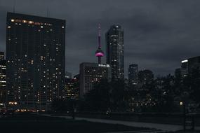 Dark cityscape with buildings, with colorful lights, under the clouds