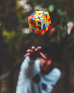 Smiling man, throwing colorful Rubik's cube, among the colorful plants