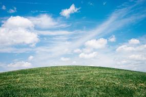 green meadow with clouds and blue sky