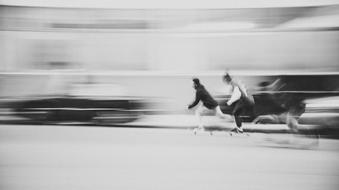 Black and white photo of the people on the skateboards, in motion