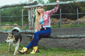 Blonde girl in hat, with the colorful, beautiful and cute dog in the village in Russia