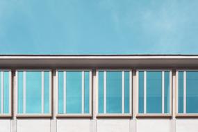 Building with windows with reflections, under the blue sky