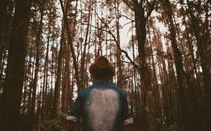 man in denim jacket in dark forest