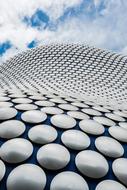 Design of the building with shiny circles, under the blue sky with white clouds