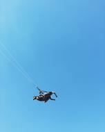 Man, flying on the parachute, in sunlight, under the blue sky