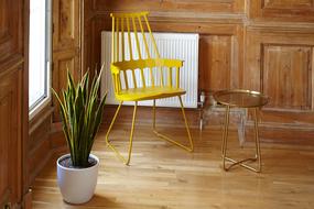 Yellow chair standing among the other furniture in the corner of the wooden room