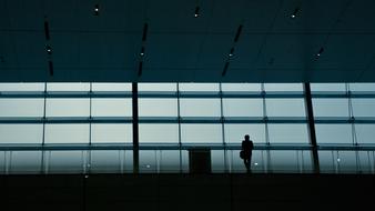 Silhouette of the person, looking out of the dark building with windows