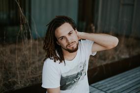 photo of a guy with African pigtails sitting on a bench