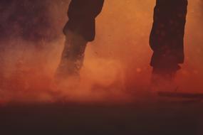 Legs and feet of the person, among the orange and red smoke