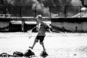 black and white photo of a boy walking on stones