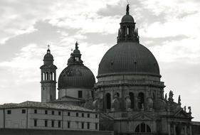 Black and white photo of the beautiful church with dome, under the sky with clouds, in Venice, Italy