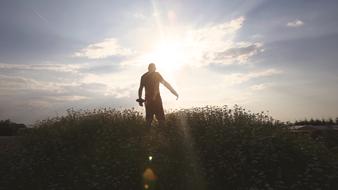 Silhouette of a man on the grass field, in beautiful sunlight