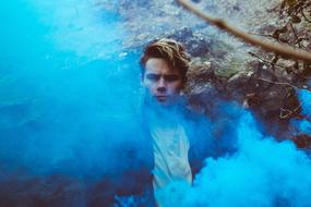 young Man behind blue smoke