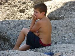 pensive boy on big stones