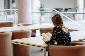 girl with a book on an armchair at the table