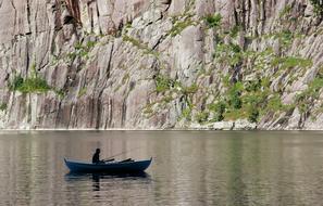fisherman in a boat on the lake against the background of high mountains