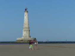 Landscape with the people near the lighthouse in Gironde, France, under the blue sky