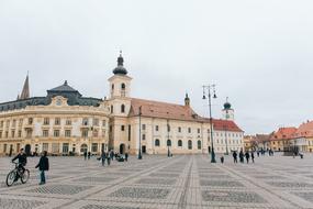 Beautiful landscape of the square with people, among the colorful buildings, under the sky with clouds