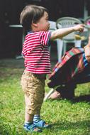 Child, standing on the green grass, on the sunny day