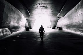 Black and white photo with the silhouette of the person, in the tunnel with light