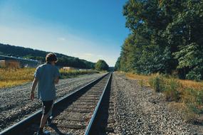 guy walks on rails on a sunny day