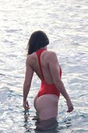 Girl in red swimming suite standing in water