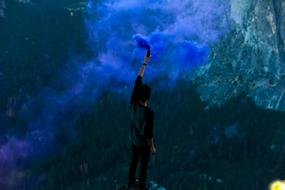 man with Blue colored Smoke bomb at mountains