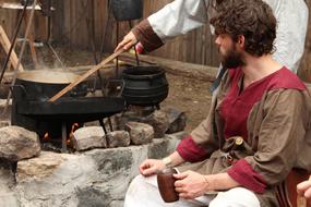 men cook food over a campfire