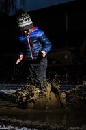 Child in hat, walking in the puddle, among the darkness, in winter