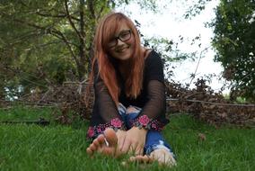 Young, redhaired, smiling teen girl on the green grass