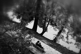 Black and white photo of the beautiful park with the people, sitting on the bench, near the river